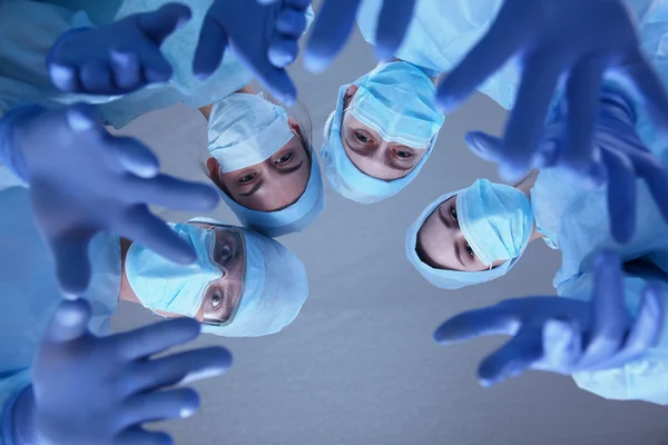 Equipo de cirujanos, con uniformes de protección, gorras y máscaras —  Fotos de Stock