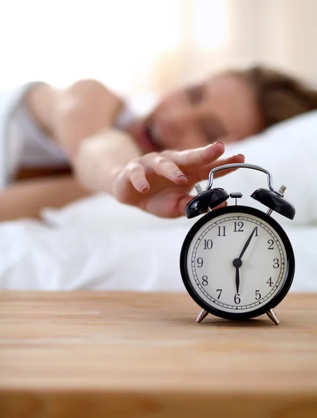 Young sleeping woman and alarm clock in bedroom at home Stock Image