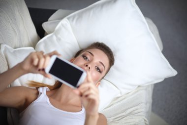 Yatak odasında cep telefonu ile kendini bir fotoğraf çekici mutlu esmer