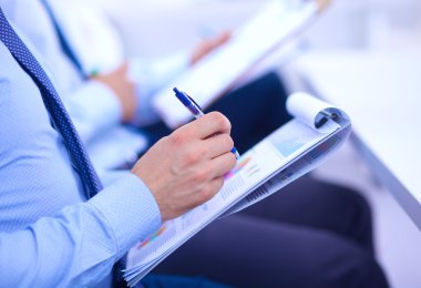 İş toplantılarında, ofiste oturan ve yazan iş adamları.