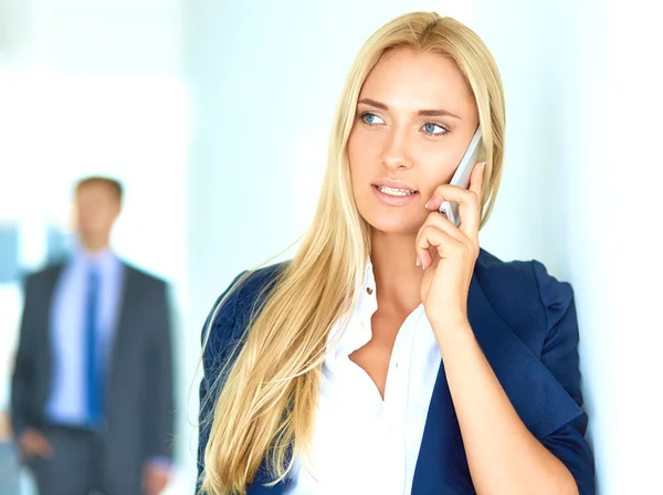 Бизнесмен, стоящая у окна офиса и разговаривающая по мобильному телефону — стоковое фото