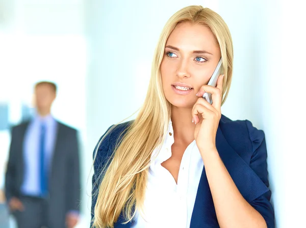 Zakenvrouw staat tegen kantoorraam te praten op mobiele telefoon — Stockfoto