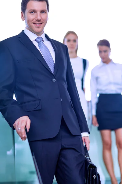 Portret van jonge zakenman in kantoor met collega's op de achtergrond — Stockfoto