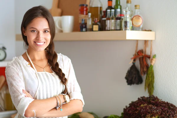 Mujer joven de pie cerca de escritorio en la cocina —  Fotos de Stock