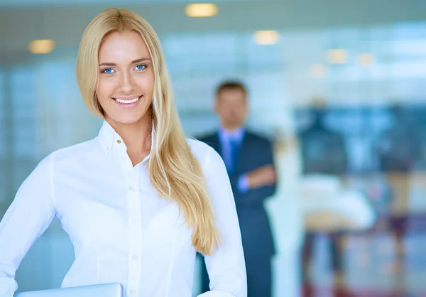 Porträtt av ung affärskvinna med laptop i office med kollegor i bakgrunden — Stockfoto