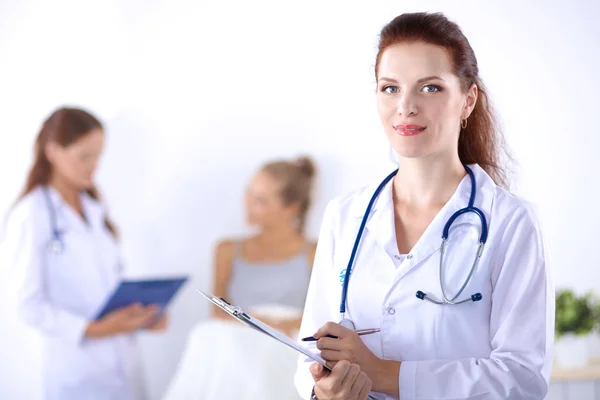 Sorridente medico donna con una cartella in uniforme in piedi in ospedale — Foto Stock