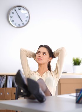 İş kadını ellerini başının arkasına koyup bir ofis sandalyesinde oturuyor.
