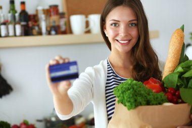 Kredi kartı ve evde mutfakta alışveriş çantası kadın ile