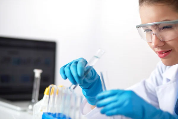 Woman researcher is surrounded by medical vials and flasks, isolated on white background — Stock Photo, Image