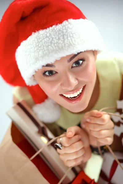 Menina feliz no chapéu de santa com caixa de presente no fundo vermelho — Fotografia de Stock