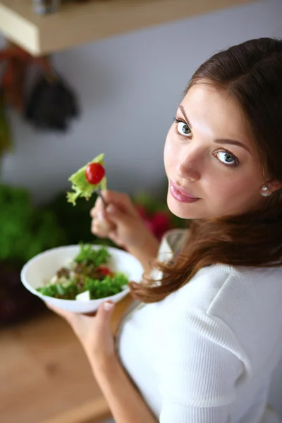 年轻女人吃沙拉和持有一份综合的沙拉 — 图库照片