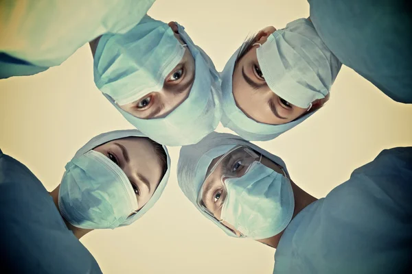 Equipo de cirujanos, con uniformes de protección, gorras y máscaras —  Fotos de Stock