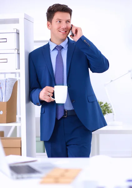 Lachende zakenman permanent en mobiele telefoon gebruiken in office — Stockfoto