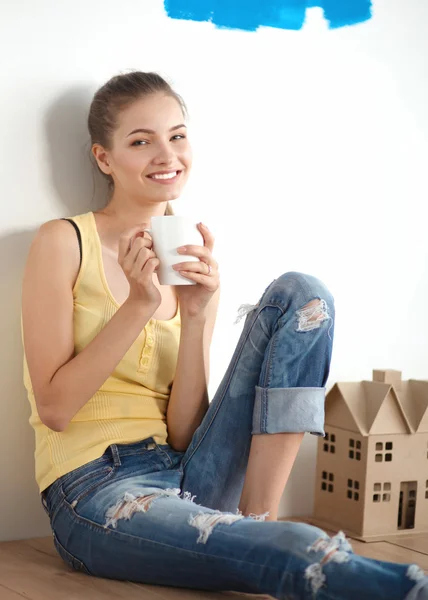 Portrait of female painter sitting on floor near wall after painting. — Stock Photo, Image