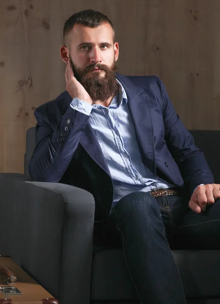 Businessman sitting the sofa in office lobby, isolated on dark background — Stock Photo, Image