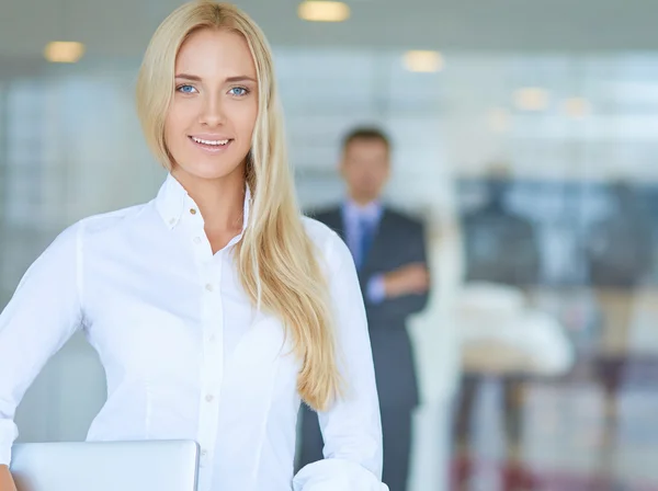 Portret van jonge zakenvrouw met laptop in kantoor met collega's op de achtergrond — Stockfoto