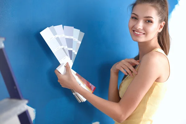 Jovem bela mulher segurando paleta de cores, de pé perto da parede . — Fotografia de Stock