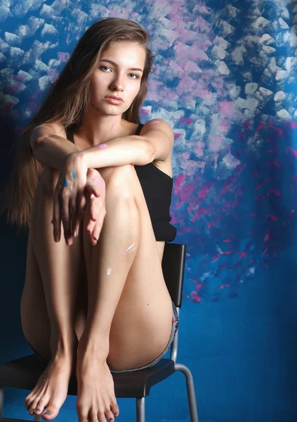 絵画の壁の近くに座っている若い女性 — ストック写真