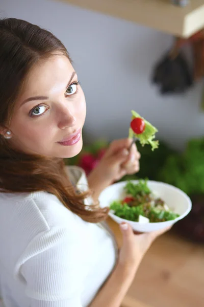 Jeune femme mangeant de la salade et tenant une salade mixte — Photo