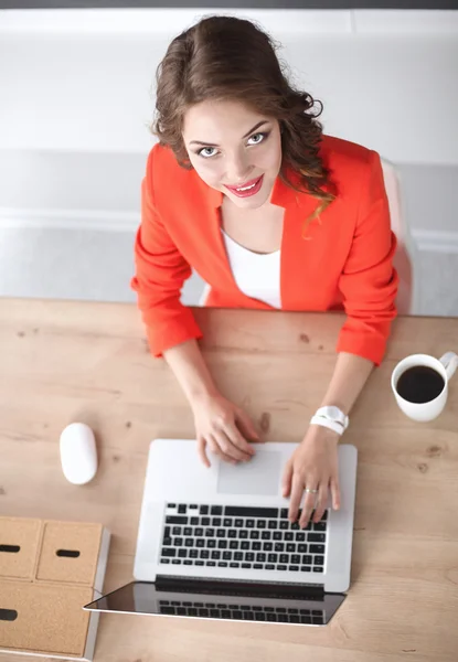 Mulher atraente sentada na mesa no escritório, trabalhando com computador portátil — Fotografia de Stock