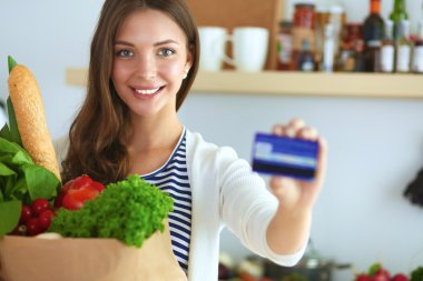 Kredi kartı ve evde mutfakta alışveriş çantası kadın ile