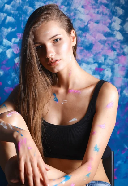 Young woman sitting near painting wall — Stock Photo, Image