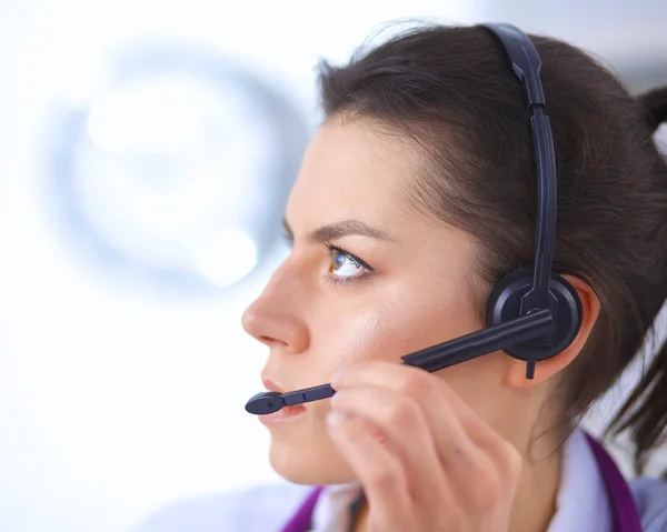 Médico con auriculares sentado detrás de un escritorio con portátil — Foto de Stock