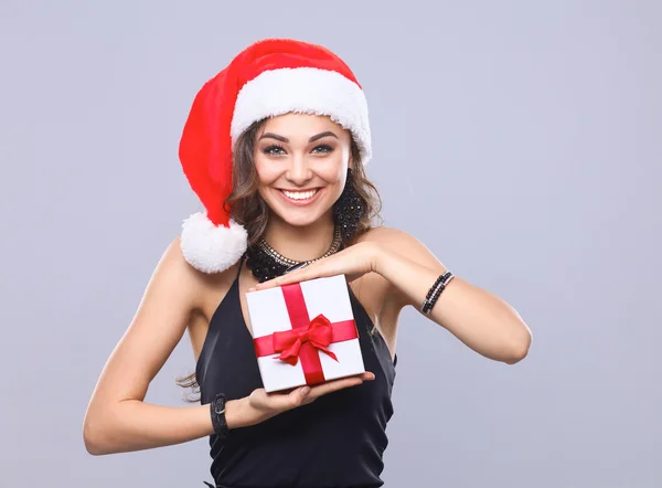 Donna in cappello Babbo Natale in possesso di doni, isolato su grigio — Foto Stock