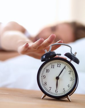 Evdeki yatak odasında uyuyan genç kadın ve çalar saat.