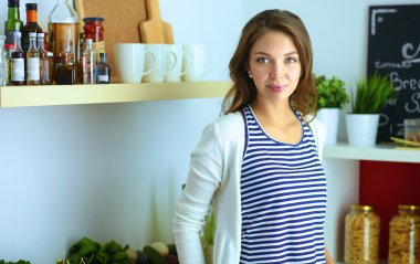 Genç bir kadın mutfakta duruyor.