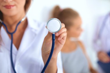 Steteskopla dinleyen kadın doktor, gri arka planda izole edilmiş.