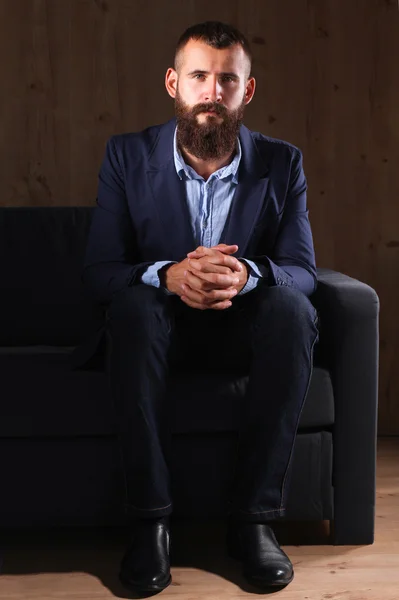 Businessman sitting the sofa in office lobby, isolated on dark background — Stock Photo, Image