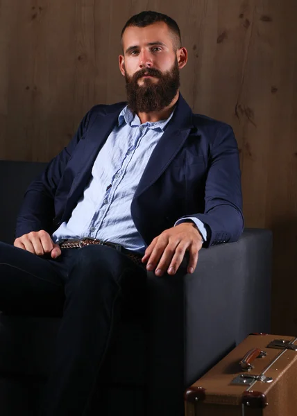 Businessman sitting the sofa in office lobby, isolated on dark background — Stock Photo, Image