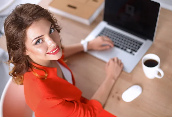 Mulher atraente sentada na mesa no escritório, trabalhando com computador portátil — Fotografia de Stock