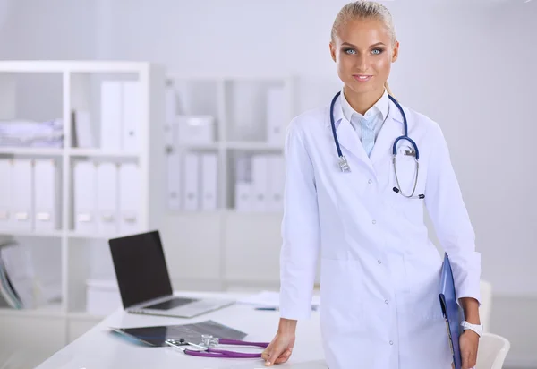 Attractive young businesswoman standing near desk with folder in the office — Stock Photo, Image