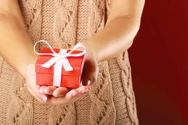 Female hand holding gift box isolated on red background — Stock Photo, Image