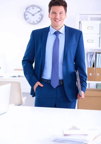 Zakenman of manager die op kantoor tegen zijn bureau staat — Stockfoto