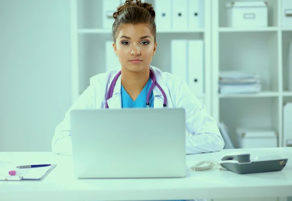 Female doctor sitting on the desk and working a laptop in hospital — Stock Photo, Image