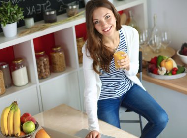 Dizüstü bilgisayar kullanarak ve mutfakta oturmuş çekici genç kadın