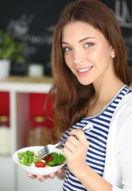 Salata yemek ve karışık salata tutan genç kadın