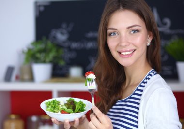Salata yemek ve karışık salata tutan genç kadın