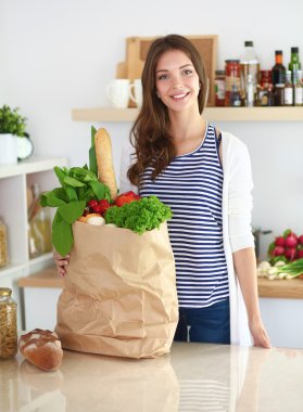 Genç bir kadın mutfakta duruyor.