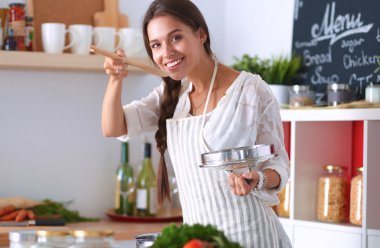Mutfakta ahşap kaşıkla yemek pişiren kadın