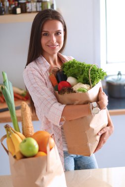 Elinde sebzeli alışveriş torbası tutan genç bir kadın.