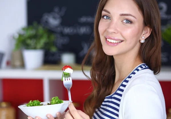 Jovem comendo salada e segurando uma salada mista — Fotografia de Stock