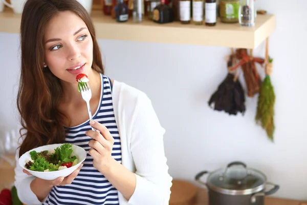 Junge Frau isst Salat und hält einen gemischten Salat in der Hand — Stockfoto