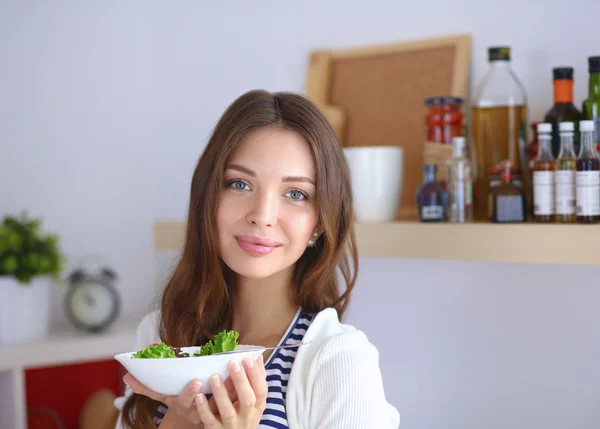 Jovem comendo salada e segurando uma salada mista — Fotografia de Stock