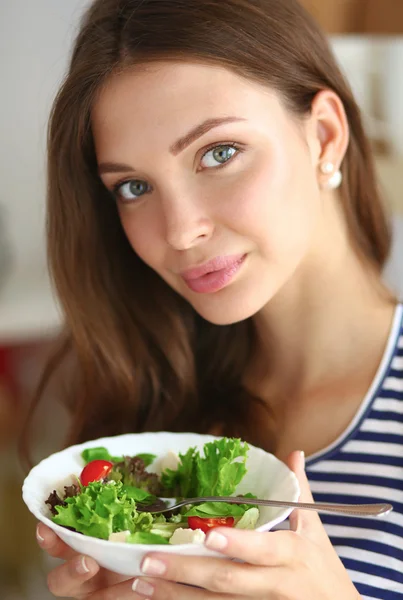 Ung kvinna äta sallad och hålla en blandad sallad — Stockfoto