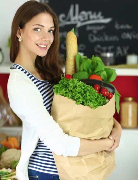 Ung kvinna som håller i matkassen med grönsaker — Stockfoto