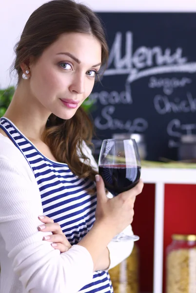 Mulher bonita bebendo um pouco de vinho em casa na cozinha — Fotografia de Stock